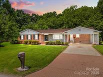 Charming brick home with manicured lawn, covered carport, and a classic American style at 303 Jean Ave, Kannapolis, NC 28083
