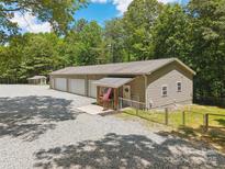 Spacious three-car garage featuring a gravel driveway and a charming covered entryway with an American flag at 364 Luther Dr, Iron Station, NC 28080
