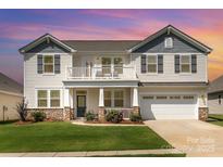 Charming two-story home with a balcony, well-manicured lawn, and stone accents at 7414 Meridale Forest Dr, Charlotte, NC 28269
