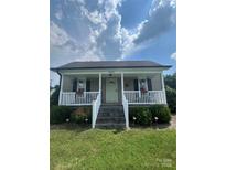Charming home featuring a welcoming front porch with white railings and meticulously maintained landscaping at 8720 Lee St, Mount Pleasant, NC 28124