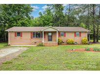 Charming brick home with red shutters and mature trees offers a welcoming front yard at 925 Rock Grove Church Rd, Salisbury, NC 28146