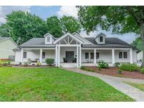 Charming white brick home boasts a covered front porch, dormer windows, and mature landscaping at 1121 S Wendover Rd, Charlotte, NC 28211