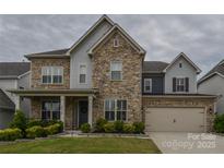 Beautiful two-story home featuring a stone facade, manicured lawn, and attached two-car garage at 15216 Shallow Ridge Rd, Charlotte, NC 28278