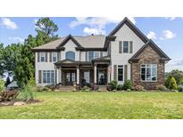 Beautiful two-story home with a manicured lawn, stone accents, and decorative shutters at 18745 Bluff Point Rd, Cornelius, NC 28031