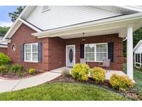 Charming brick home featuring a cozy front porch with tasteful landscaping and decorative front door at 207 Crystal Springs Ln, Shelby, NC 28150
