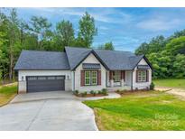 Charming single-story home with a gray roof, brick accents, and an attached two-car garage at 501 Old Speedway Nw Dr # 1, Concord, NC 28027