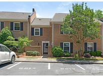 Charming brick townhouse with dark shutters, landscaping, and reserved parking spaces out front at 6817 Dumbarton Dr, Charlotte, NC 28210