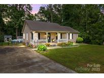 Charming home featuring a cozy front porch, lush lawn, and metal roof at 716 Mooresville Rd, Salisbury, NC 28144