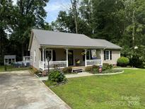 Charming single-story home with a metal roof, inviting front porch, and well-manicured landscaping at 716 Mooresville Rd, Salisbury, NC 28144