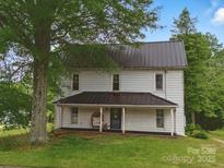 Charming two-story home with a metal roof, inviting porch, and mature trees in a serene setting at 828 N Main St, Mount Pleasant, NC 28124
