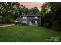 Charming blue two-story home featuring a cozy front porch and lush green lawn at 8338 Rittenhouse Cir, Charlotte, NC 28270