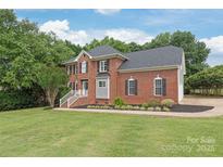 Charming two-story brick home with a lush lawn and mature trees, offering classic curb appeal at 9004 Lauriston Pl, Mint Hill, NC 28227