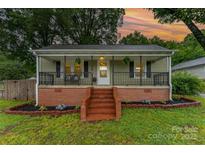 Charming single-story home featuring a welcoming front porch with decorative railings and manicured landscaping at 910 W A St # 9, Kannapolis, NC 28081