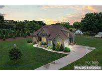 Beautiful exterior elevation of a two-story home showcasing stone accents, manicured lawn, and a paved driveway at 9125 Dylan Ridge Ct, Concord, NC 28027
