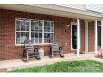 Inviting front porch features brick facade, rocking chairs, and a cozy, welcoming atmosphere at 10548 English Setter Way, Charlotte, NC 28269