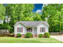 Charming single-story home with well-manicured lawn, covered front porch, and lush green trees at 110 Eighth St, York, SC 29745