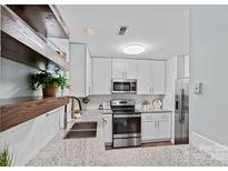 Charming kitchen features white cabinets, stainless steel appliances, granite countertops, and wood floating shelves at 3308 Selwyn Farms Ln # 5, Charlotte, NC 28209
