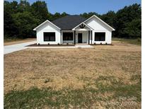 Charming, modern farmhouse with board and batten siding, a black roof and freshly laid driveway at 420 Sloop St, China Grove, NC 28023