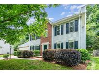 Charming two-story home with landscaped yard, brick accent, black shutters, and vibrant green foliage at 6033 Edinmeadow Ln, Charlotte, NC 28269