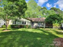 Charming single-story home with a well-maintained lawn and inviting curb appeal surrounded by mature trees at 6231 Coach Hill Ln, Charlotte, NC 28212