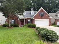 Charming single-Gathering brick home featuring a manicured lawn and two-car garage at 9419 Olivia Ln, Charlotte, NC 28277