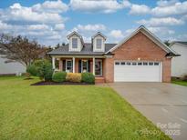 Charming brick home featuring a well-manicured lawn, two-car garage, and inviting front porch at 1209 Pressley Downs Se Dr, Concord, NC 28025
