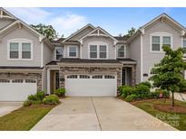 Charming townhome featuring a two-car garage, stone accents, and manicured landscaping at 12205 Gambrell Dr, Charlotte, NC 28278