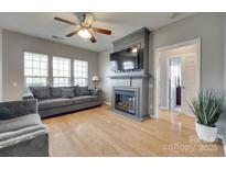 Cozy living room features a fireplace with TV, ceiling fan, and hardwood floors at 14979 Santa Lucia Dr # 2408, Charlotte, NC 28277