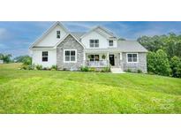Charming two-story home with a stone and white exterior, lush green lawn, and inviting front porch at 164 Vance Farm Dr, Statesville, NC 28625