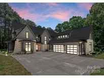 Stunning exterior featuring a modern design with stone accents, three-car garage, and a spacious driveway at 20000 Schooner Dr, Cornelius, NC 28031