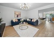 Bright living room featuring hardwood floors, modern lighting, comfortable blue sofas, and open layout to the kitchen at 2324 Brookview Ct, Rock Hill, SC 29732