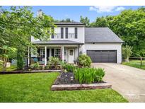 Charming two-story home with manicured lawn and a welcoming front porch and gray siding and black shutters at 4236 Carrington Sw Ct, Concord, NC 28027