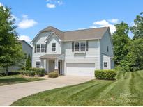 Well-manicured lawn and landscaping surround this light blue two-story home with a two-car garage at 4576 Fox Ridge Ln, Fort Mill, SC 29707