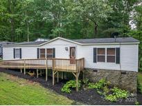 Charming home with a front porch, white siding, stone foundation, and surrounded by lush greenery at 6903 Knottywood Ln # 21, Vale, NC 28168