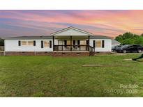 Charming ranch-style home with a welcoming front porch, lush lawn, and classic white siding at 7990 W Nc 152 Hwy, Mooresville, NC 28115