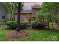 Backyard view showcasing the home's exterior, a spacious deck, and lush green lawn with mature trees at 8968 St Croix Ln, Charlotte, NC 28277