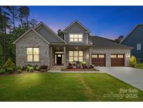 Charming brick home showcasing a manicured lawn and a welcoming three-car garage, blending style and functionality at 9833 Ardley Park Way, Mint Hill, NC 28227