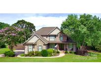 Charming two-story home featuring brick accents, a manicured lawn, mature trees, and a welcoming front porch at 141 Weathers Creek Rd, Troutman, NC 28166