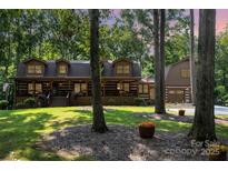 Charming log home with a covered porch, lush lawn, and mature trees at 2709 Blythe Rd, Waxhaw, NC 28173