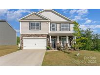 Two-story home featuring stone accents, a two-car garage, and a well-manicured lawn at 347 Carolina Hemlock Dr # 141, Locust, NC 28097