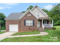 Charming brick home features an attached garage, inviting porch, and well-manicured lawn at 5111 Clearwater Rd, Charlotte, NC 28217