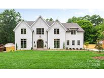 Stunning white brick home featuring a manicured lawn, arched entry and well-placed landscaping at 5127 Lansing Dr, Charlotte, NC 28270