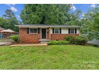 Charming single-story brick home featuring black shutters and a well-maintained front yard at 711 September Ln, Charlotte, NC 28208