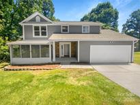 Charming gray two-story home featuring a screened porch, manicured lawn, and attached two-car garage at 7737 Batavia Ln, Charlotte, NC 28213