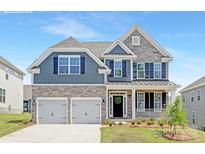 Charming two-story home showcases stone accents, blue siding, a two-car garage, and a cozy front porch at 8000 Plymouth Dr, Sherrills Ford, NC 28673