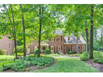Stately two-story brick home featuring mature trees, lush landscaping, and a charming front garden at 10215 Balmoral Cir, Charlotte, NC 28210