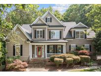 Charming two-story home featuring a red front door, manicured landscaping, and a welcoming front porch at 154 Hunters Hill Dr, Statesville, NC 28677