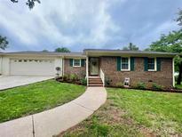 Charming brick home with a well-manicured lawn and a welcoming walkway at 311 Tiffany Nw St, Concord, NC 28027