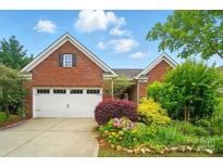 Charming brick home with a two-car garage and beautifully landscaped front yard featuring vibrant flowers and greenery at 6007 Edinburgh Ln # 214, Indian Land, SC 29707