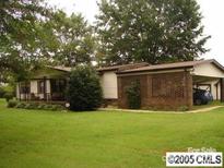 Ranch-style home with a lush lawn, mature trees, and a covered carport, offering a blend of comfort and outdoor charm at 634 Lippard Farm Rd, Statesville, NC 28625